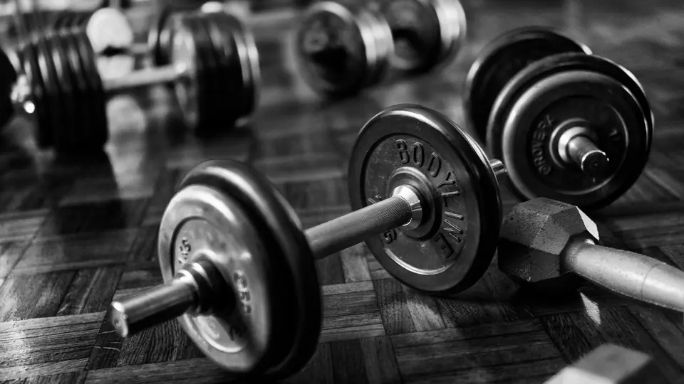 Black-and-white photo of spin-lock dumbbells on a wooden gym floor