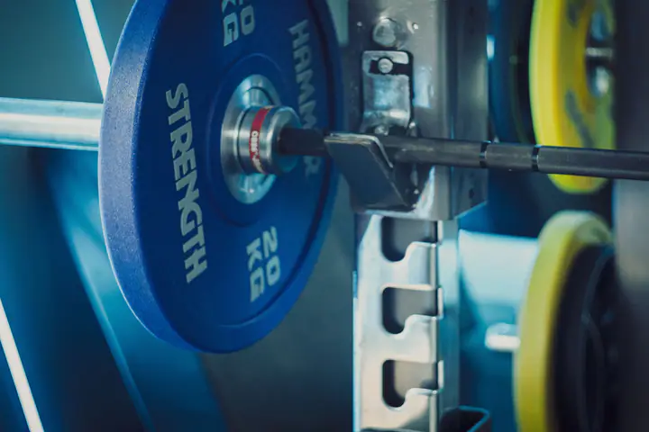 Barbell loaded with 20 kg plates resting on the J-hooks of a rack