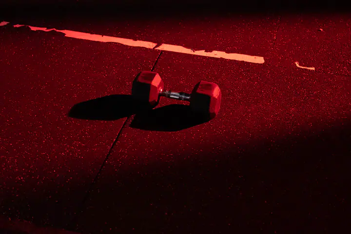 Single dumbbell on a gym floor lit by red light