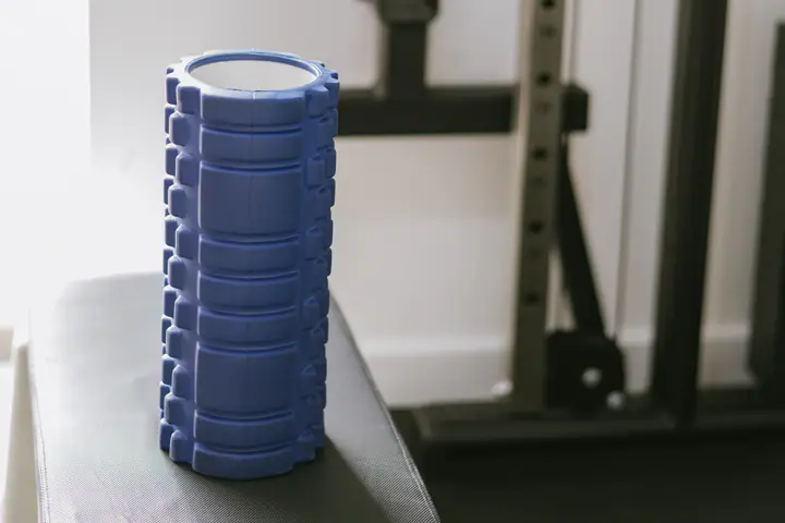 Blue foam roller standing on a plyo box next to a cable machine