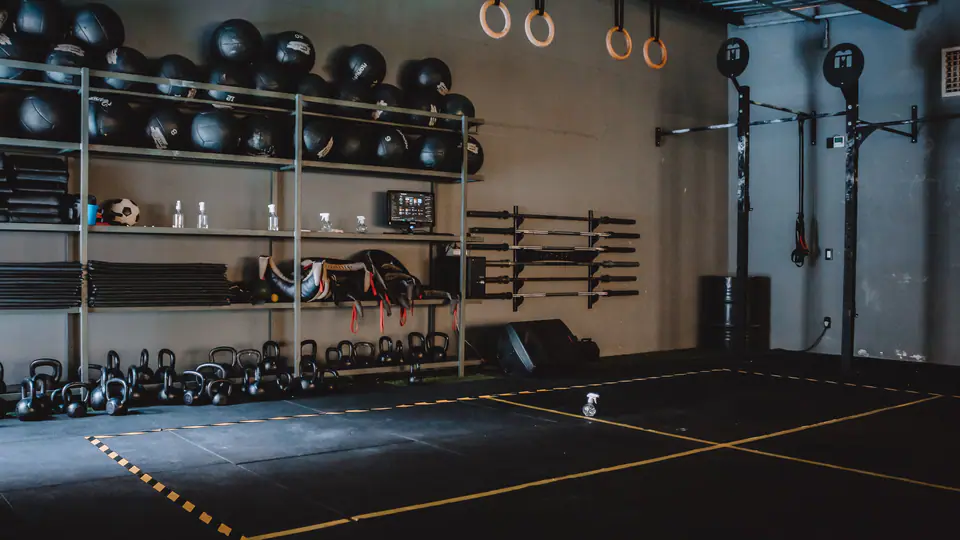 Functional training area with medicine balls, gymnastic rings, kettlebells and barbells on the wall