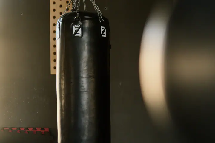 Heavy punching bag hanging on a chain in a dark gym