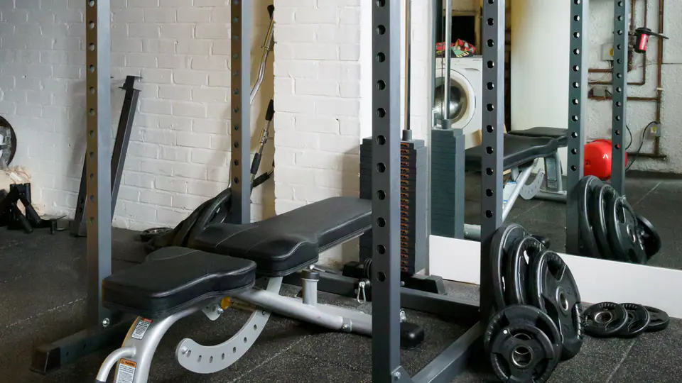 Adjustable bench set inside a power rack, with plates stacked on the storage pegs