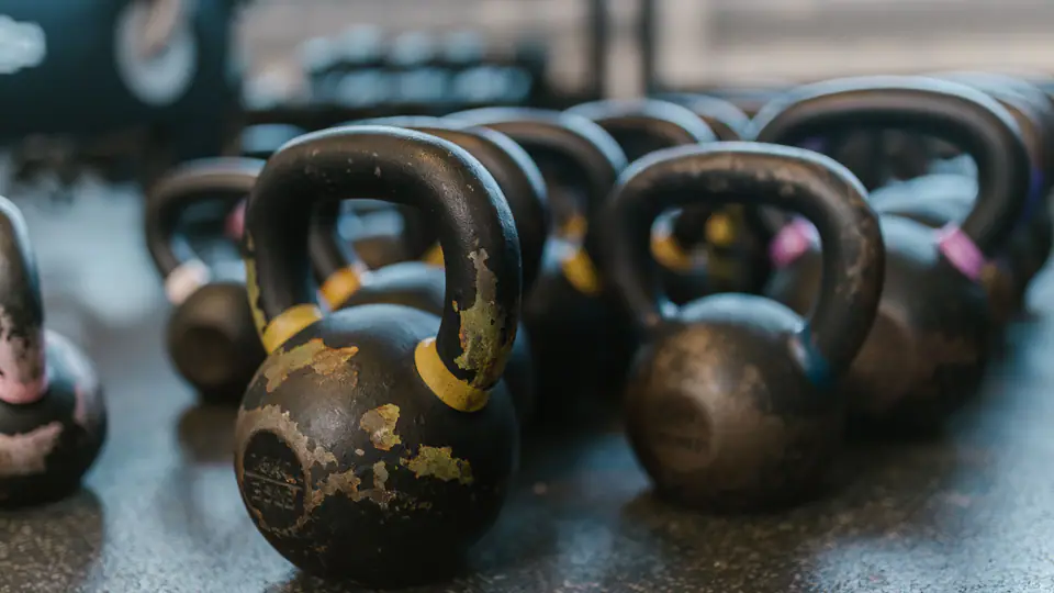 Rows of well-used kettlebells on a gym floor