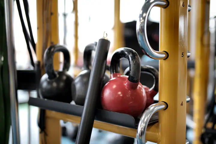 Kettlebells stored on a yellow rack in a gym