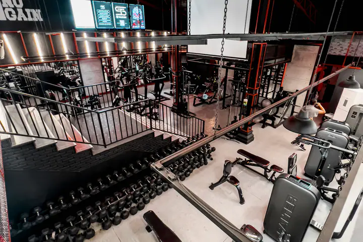 Large two-level gym seen from above, with benches, racks and dumbbells