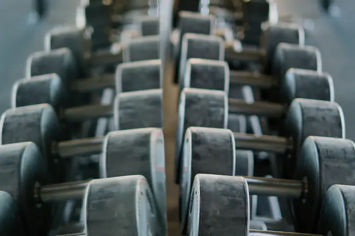 Two long rows of dumbbells on facing racks, reflected in a mirror