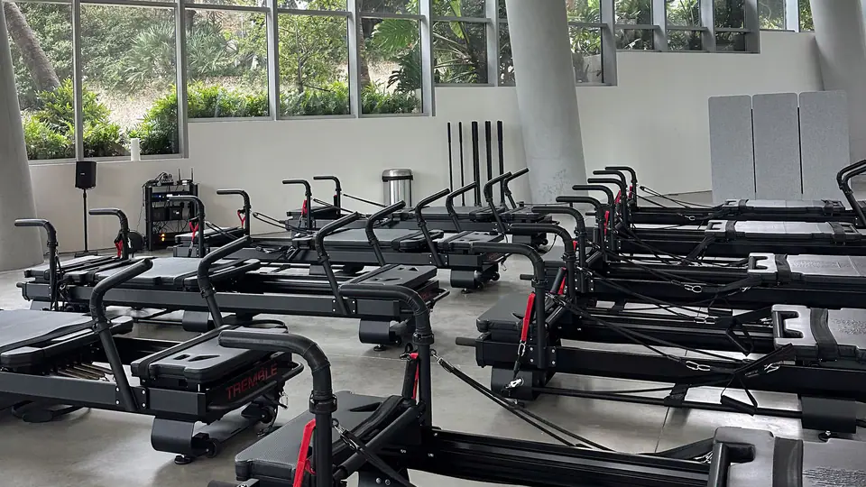 Bright studio with rows of Pilates reformers and floor-to-ceiling windows