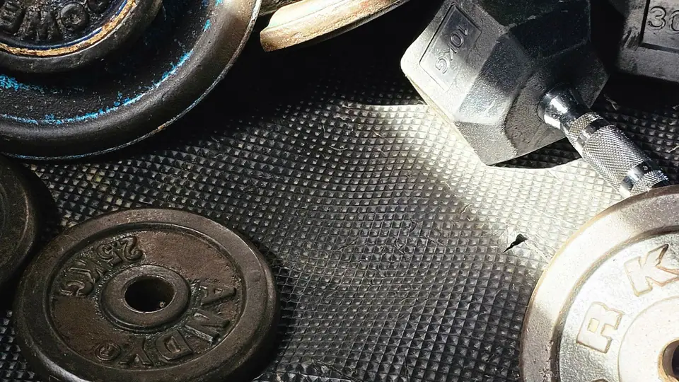 Worn cast-iron plates and dumbbells scattered on a rubber mat