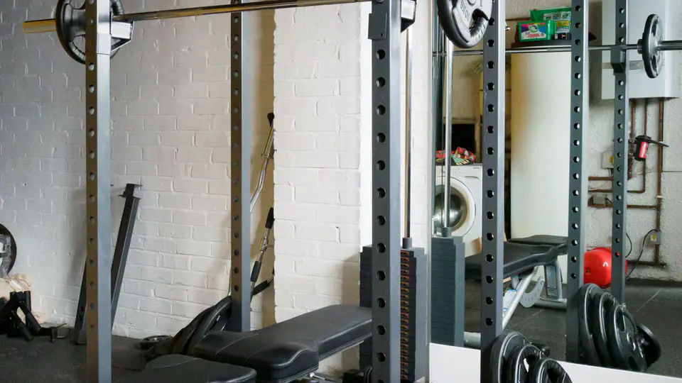 Adjustable bench set inside a power rack, with plates stacked on the storage pegs