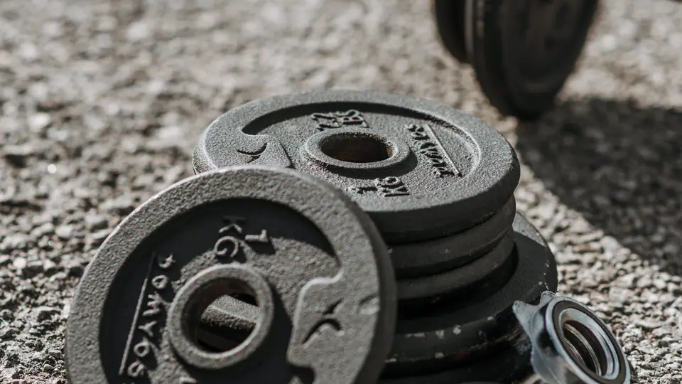 Cast-iron weight plates, spin-lock collars and a dumbbell handle on concrete
