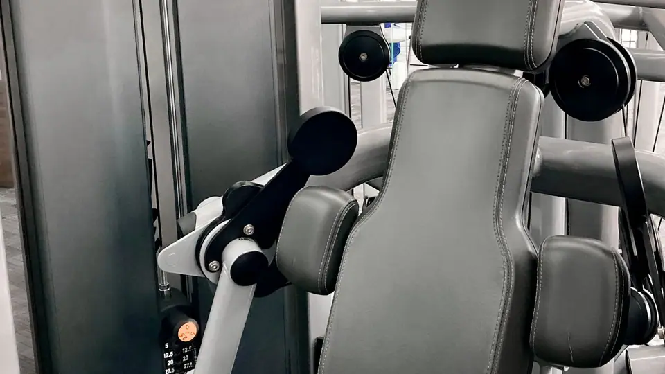Seated biceps curl machine with padded arm rest