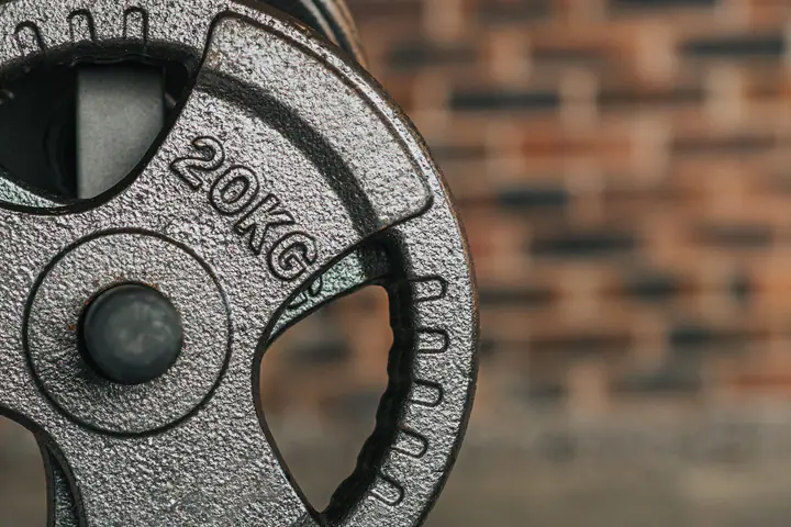 Stack of 20 kg cast-iron weight plates against a brick wall