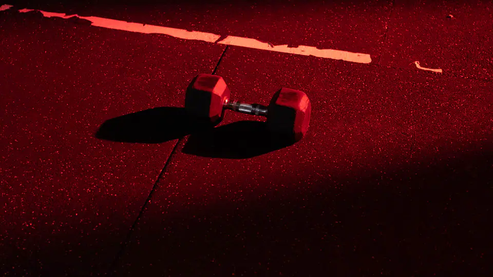 Single dumbbell on a gym floor lit by red light