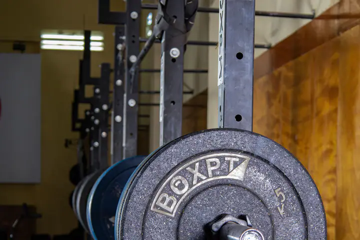 Weight plate on a barbell resting in the uprights of a rack