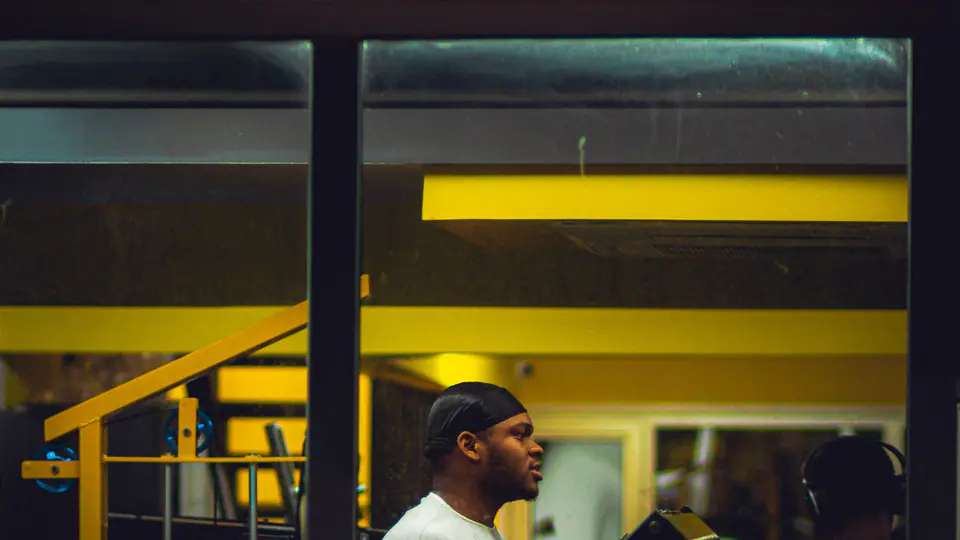 Lifters training on machines seen through a gym window at night